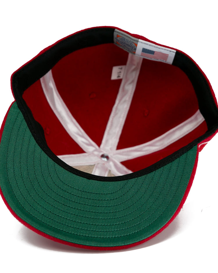 The EFF Wembley Lions 1957 Vintage Ballcap in red features a green underbrim, white stitched panels, and an inside label—a classic hand-sewn wool style inspired by British National Hockey League heritage.