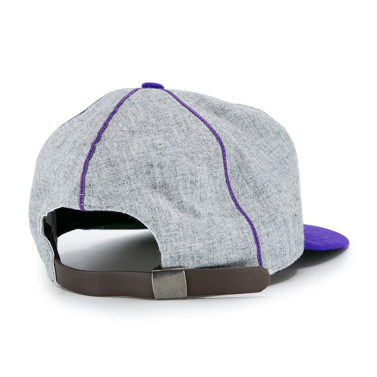 The EFF University of Washington 1938 Vintage Ballcap is a grey cap with purple stitching and brim, pictured from the back. It features an adjustable brown leather strap and metal buckle for a classic look.