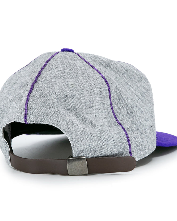 The EFF University of Washington 1938 Vintage Ballcap is a grey cap with purple stitching and brim, pictured from the back. It features an adjustable brown leather strap and metal buckle for a classic look.