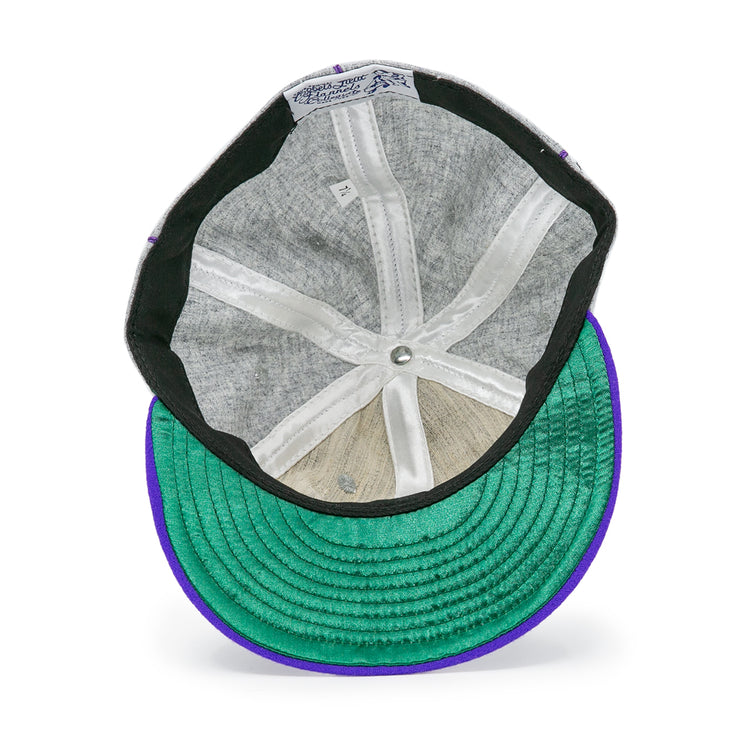 The inner view of the EFF University of Washington 1938 Vintage Ballcap features a gray lining, white seams, green underbrim, purple edge, and the manufacturers label on the inner band of this genuine wool cap.