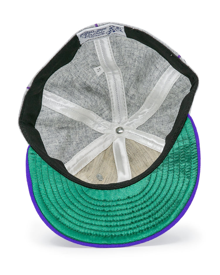 The inner view of the EFF University of Washington 1938 Vintage Ballcap features a gray lining, white seams, green underbrim, purple edge, and the manufacturers label on the inner band of this genuine wool cap.