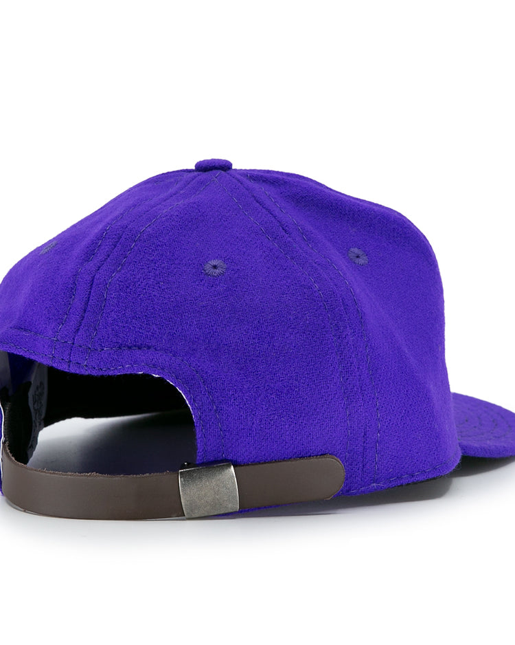 The EFF University of Washington 1950 Vintage Ballcap in purple is shown from the back, featuring a brown adjustable strap with a metal clasp. This authentic cap is crafted from genuine wool.