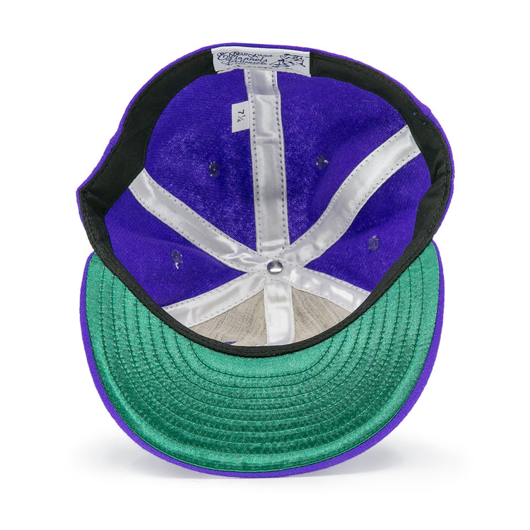 Seen from below, the EFF University of Washington 1950 Vintage Ballcap in purple features a green underbrim, white inner seams, and a size tag reading 7 1/4 on its genuine wool inner band.