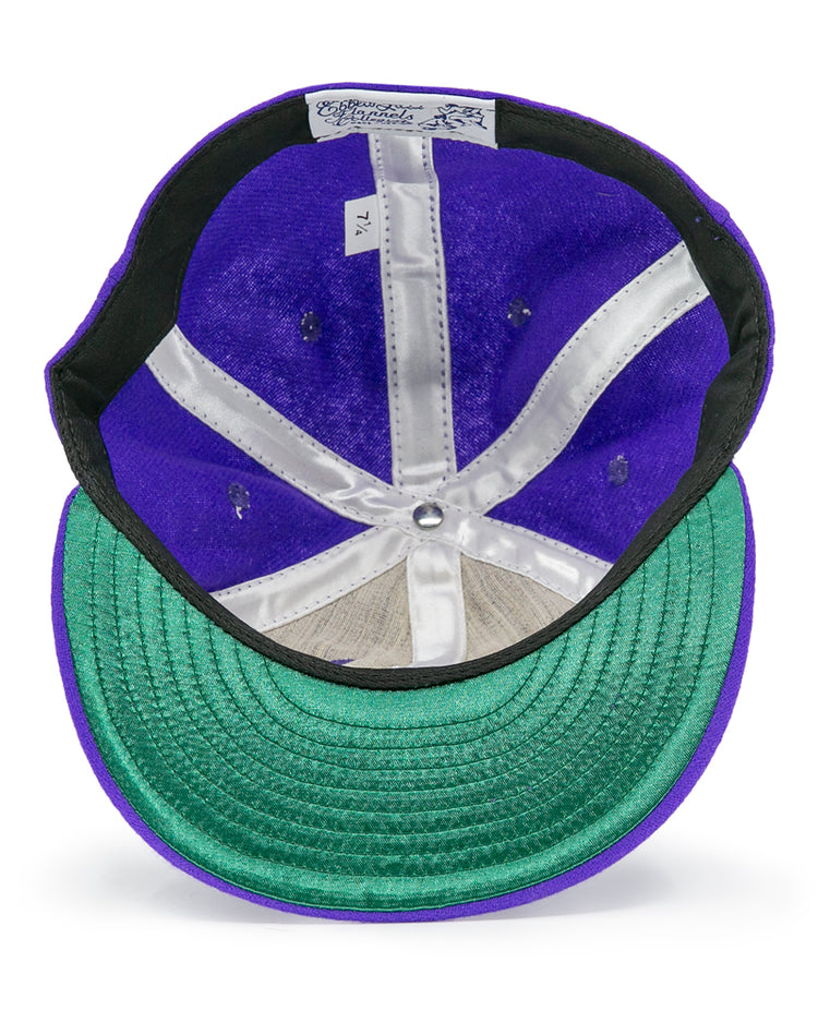 Seen from below, the EFF University of Washington 1950 Vintage Ballcap in purple features a green underbrim, white inner seams, and a size tag reading 7 1/4 on its genuine wool inner band.