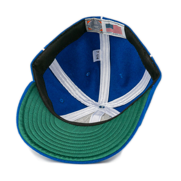The image shows the inside of an EFF Wyoming State Penitentiary 1911 Vintage Ballcap, featuring a blue crown, green brim, American flag Made in USA fabric label, and size 7 1/4 on a white tag.