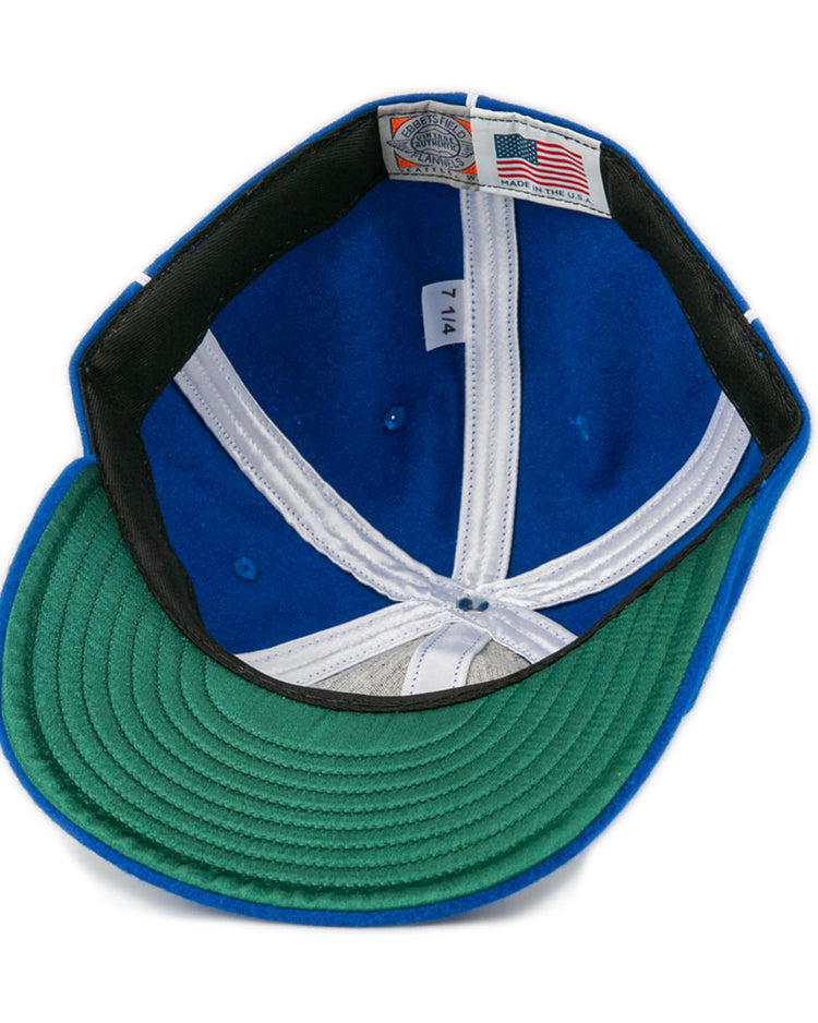 The image shows the inside of an EFF Wyoming State Penitentiary 1911 Vintage Ballcap, featuring a blue crown, green brim, American flag Made in USA fabric label, and size 7 1/4 on a white tag.