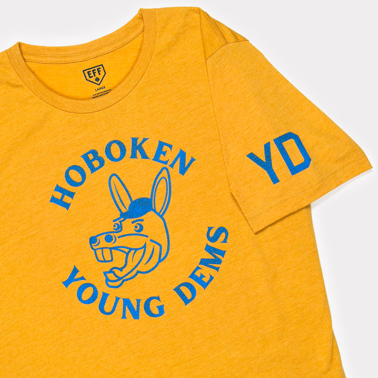 The Ebbets Field Flannels Hoboken Young Democrats T-Shirt is a yellow unisex tee with blue HOBOKEN YOUNG DEMS text around a cartoon donkey, plus blue YD on the left sleeve—great for Little League events.